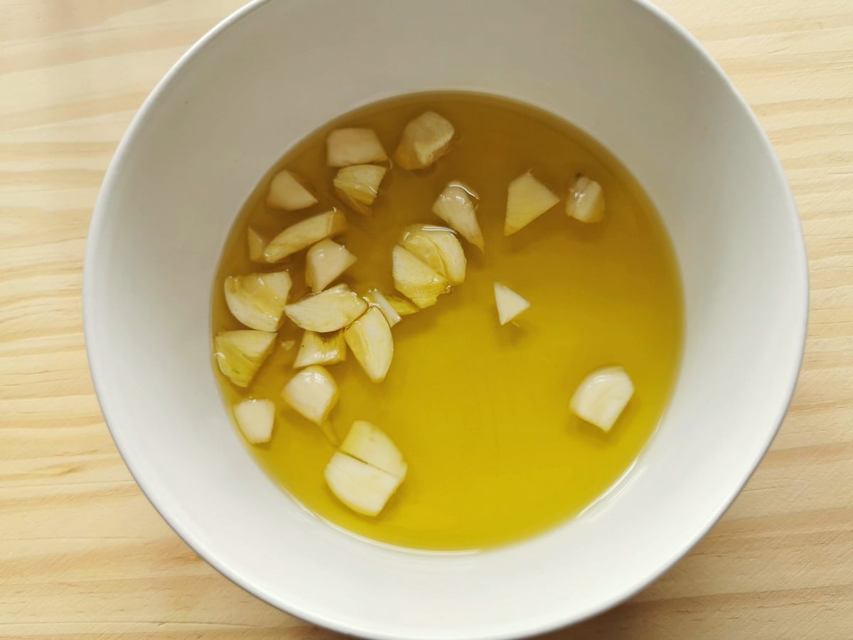 Peeled and chopped garlic in bowl of extra virgin olive oil.
