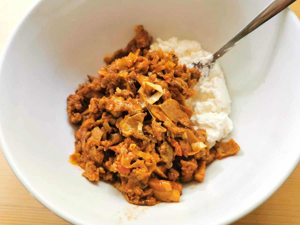 sausage and mushroom sauce in white bowl with ricotta