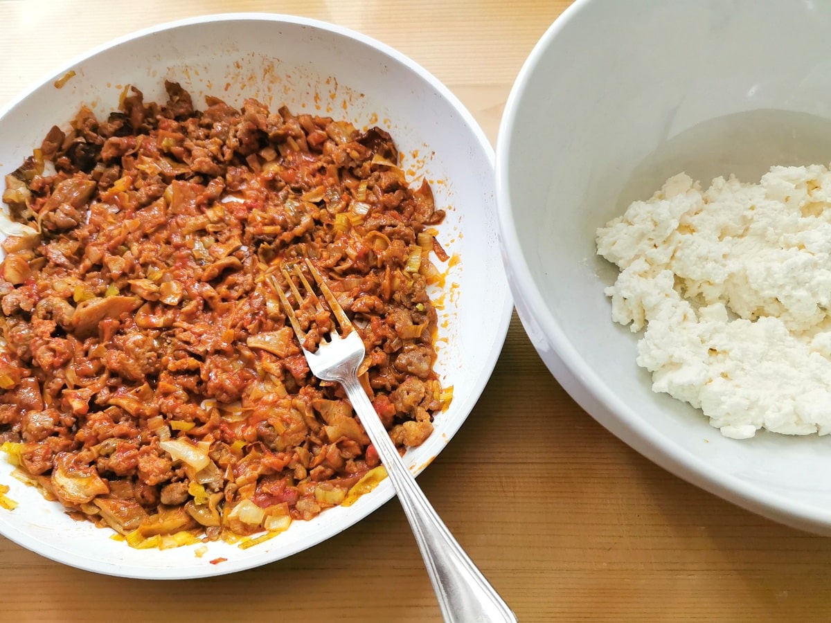 sausage and mushroom sauce in frying pan and ricotta in white bowl