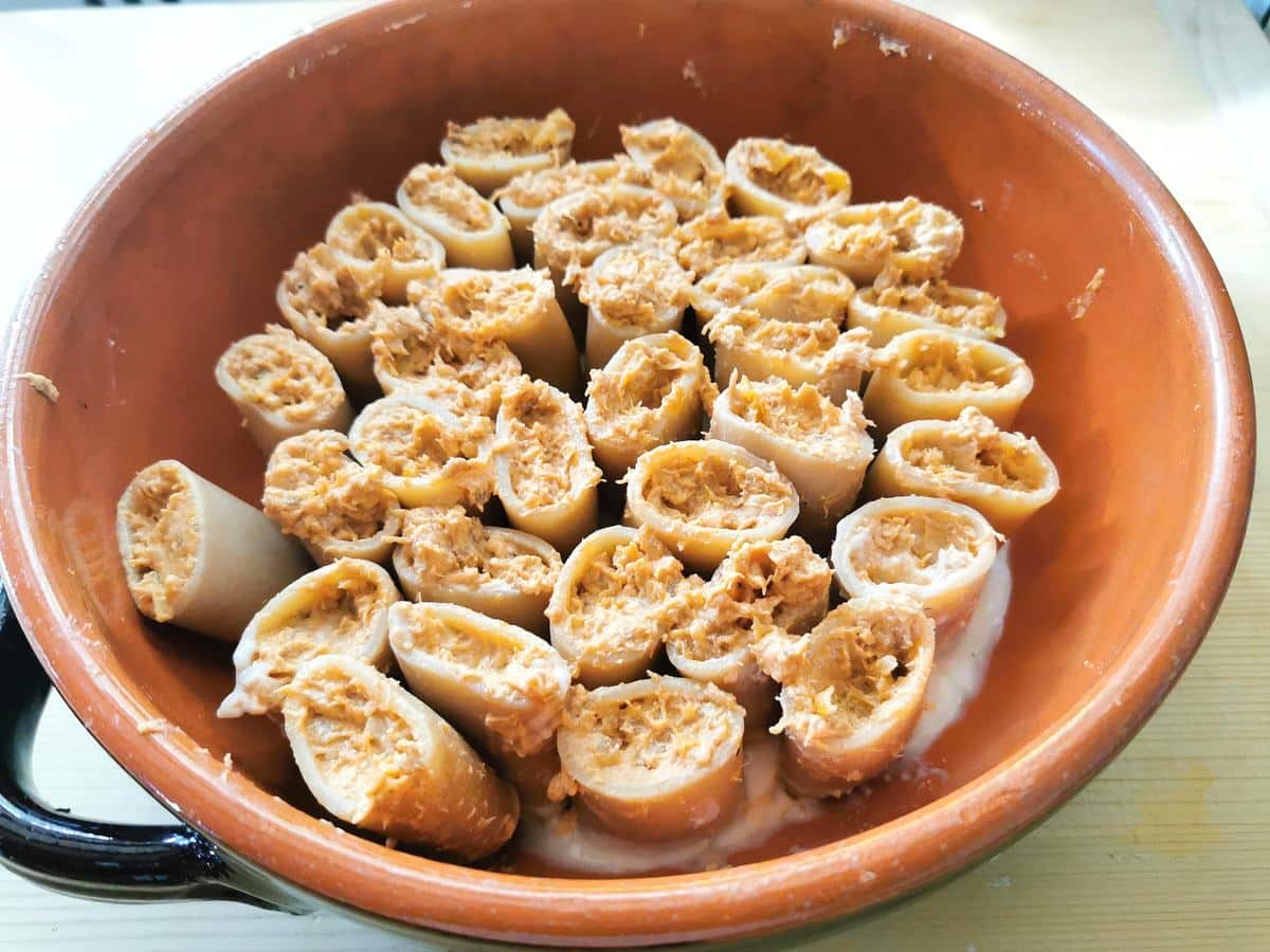 filled paccheri pasta tubes in round terracotta oven dish