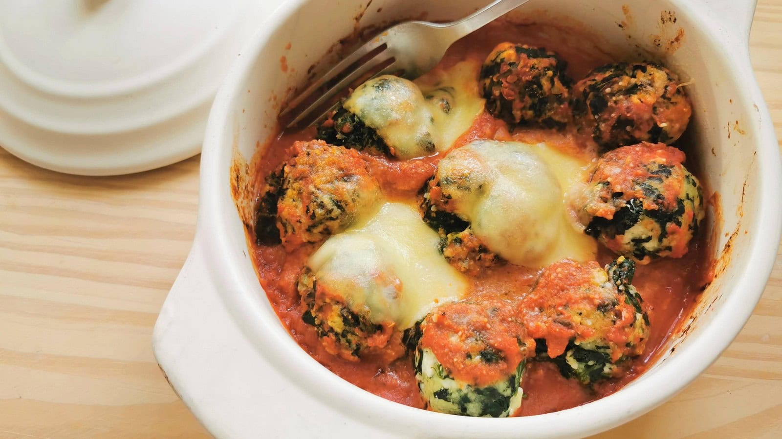 Baked Tuscan spinach and ricotta gnudi in tomato sauce.
