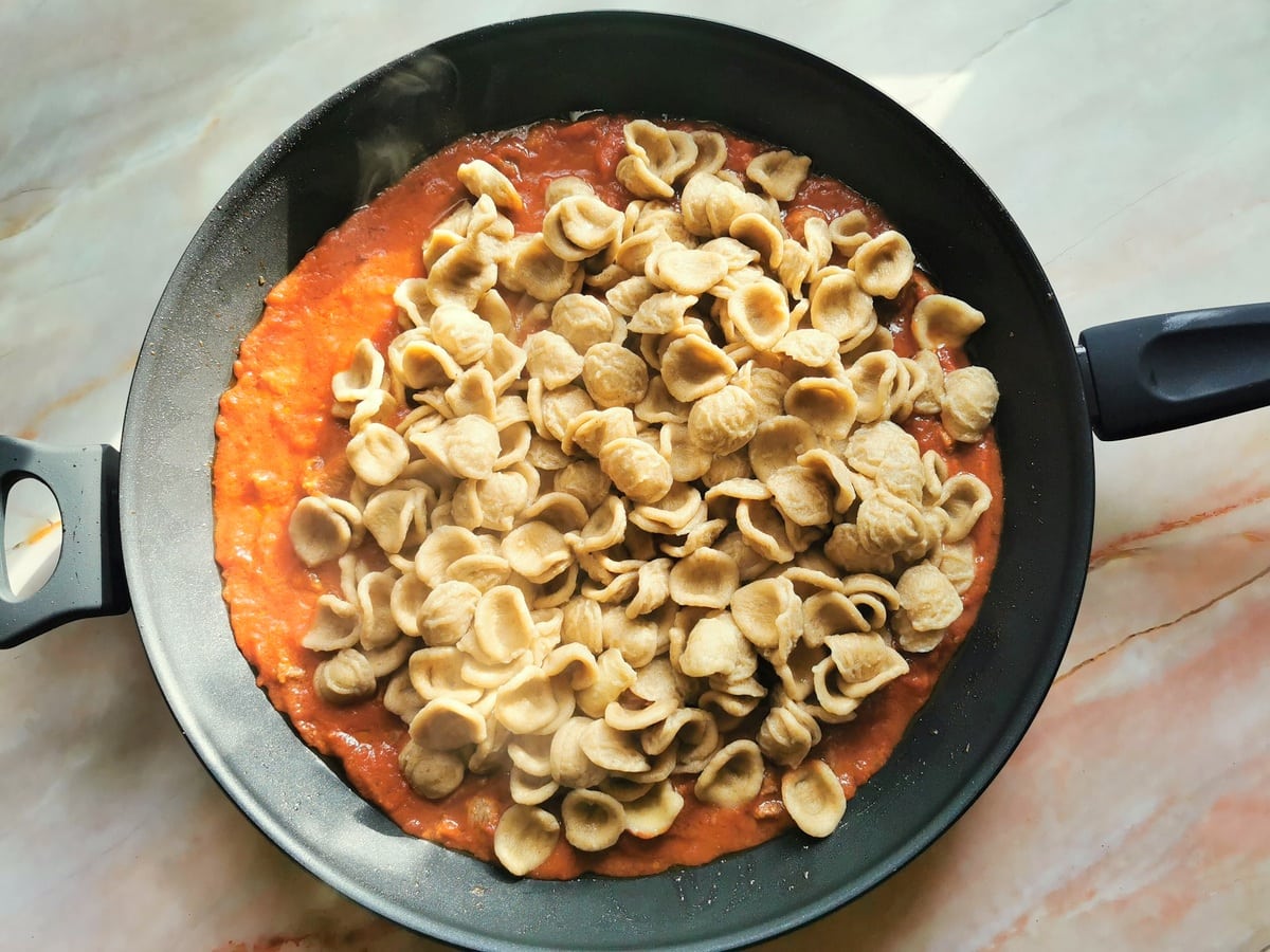 Cooked orecchiette in skillet with lamb sauce.