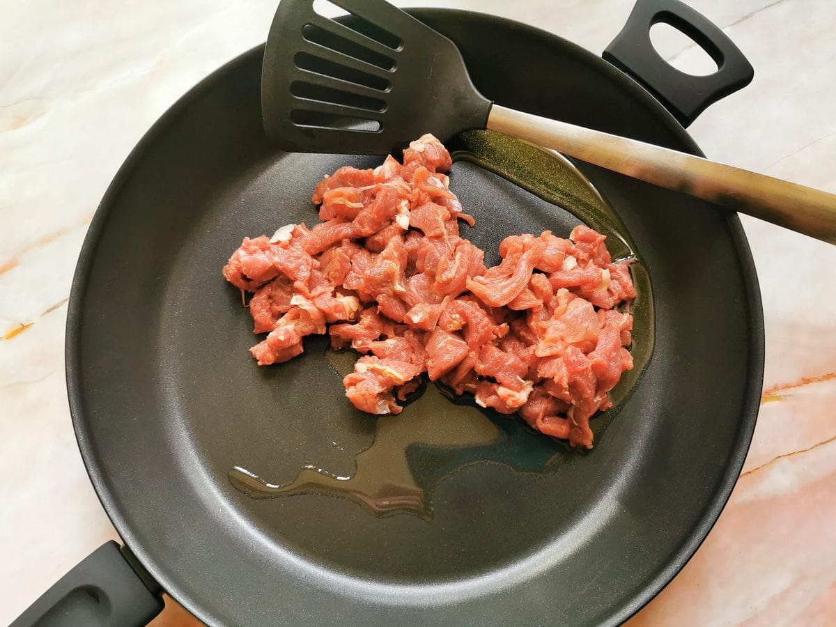 Diced lamb in skillet with olive oil.