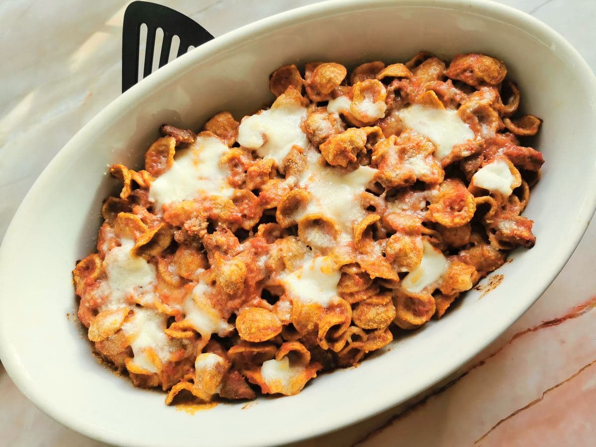 Ready baked orecchiette pasta with lamb in oval oven dish.