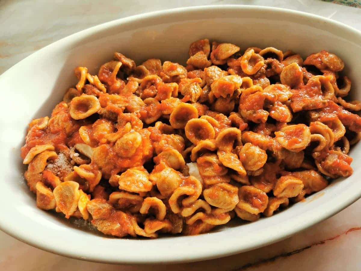 A second layer of orecchiette and lamb sauce in oval oven dish.