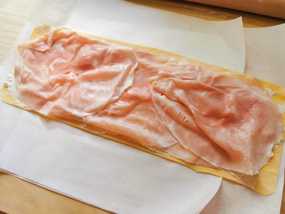 Fresh pasta sheet with stracchino and grated parmigiano covered in cooked ham slices.