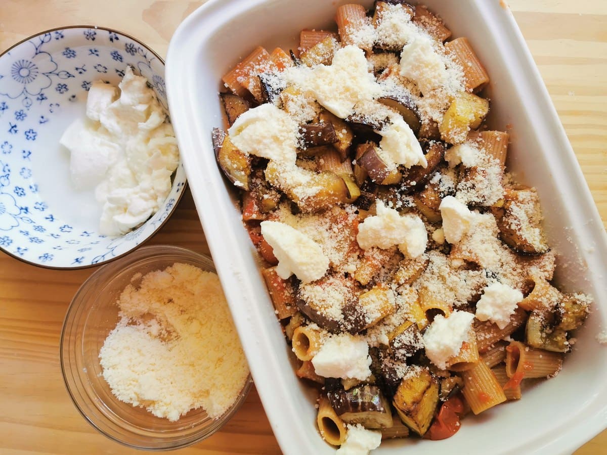 Whole wheat pasta with tomato sauce, eggplant and mozzarella in white oven dish.