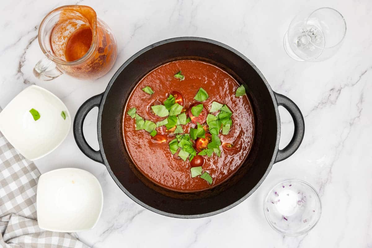 Adding tomato passata, cherry tomatoes and basil to the pot