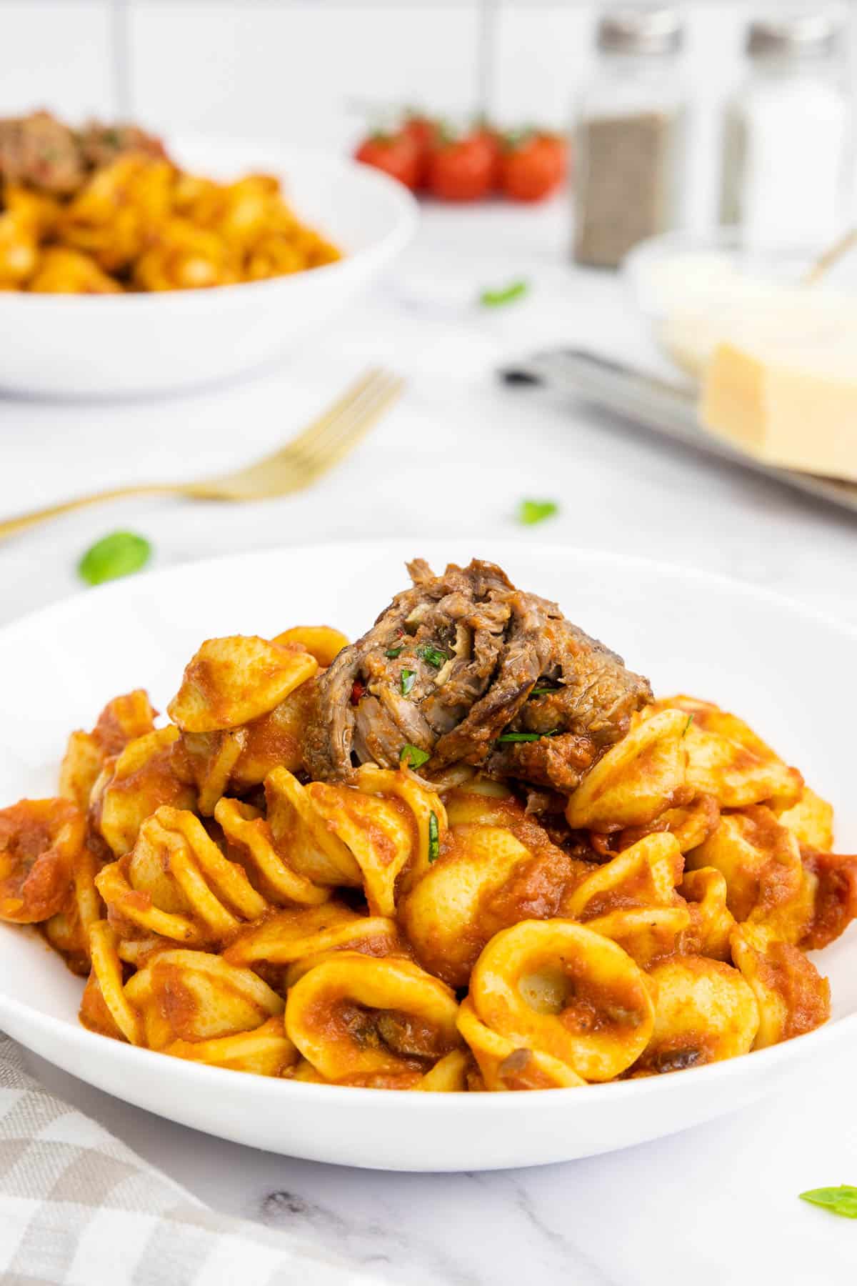 Braciole on top of a bowl of orecchiette pasta