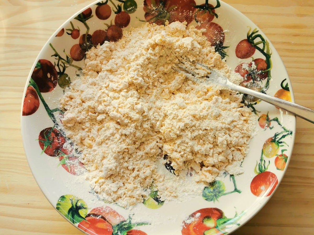 Eggs and flour mixed together in a bowl with a fork.