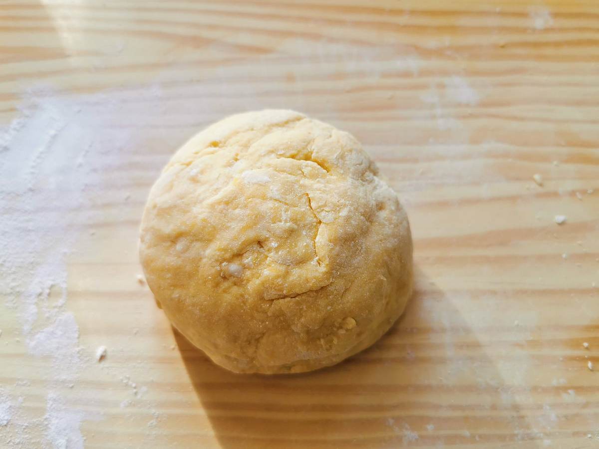 Kneaded ravioli dough ball on wood surface.