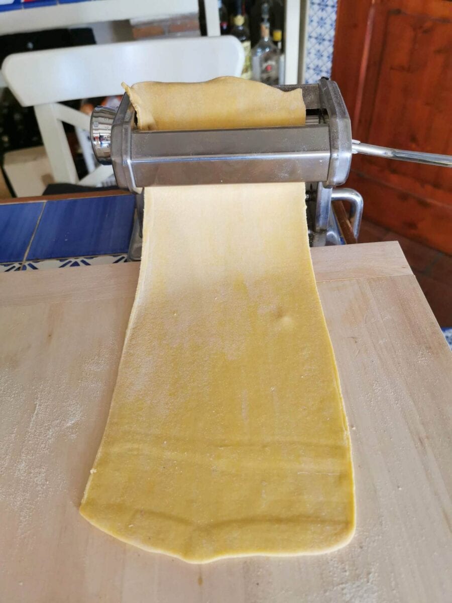 Pasta dough sheet passing through pasta machine.