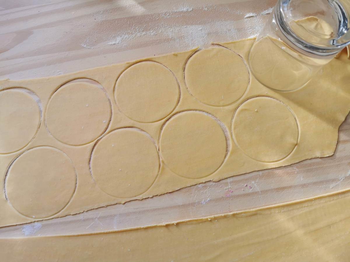 Sheet of pasta dough cut into circles with a glass.