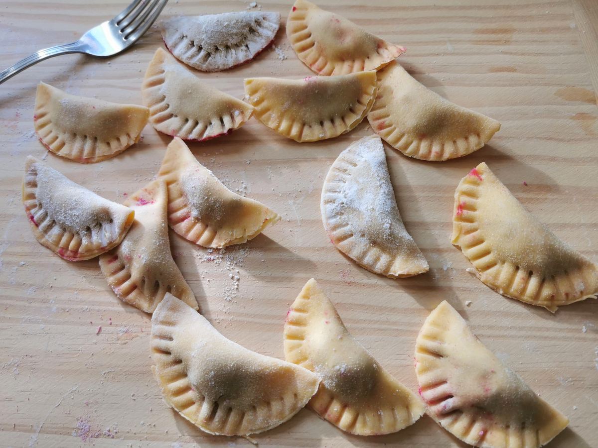 Ready beetroot ravioli with a fork used to crimp the edges.