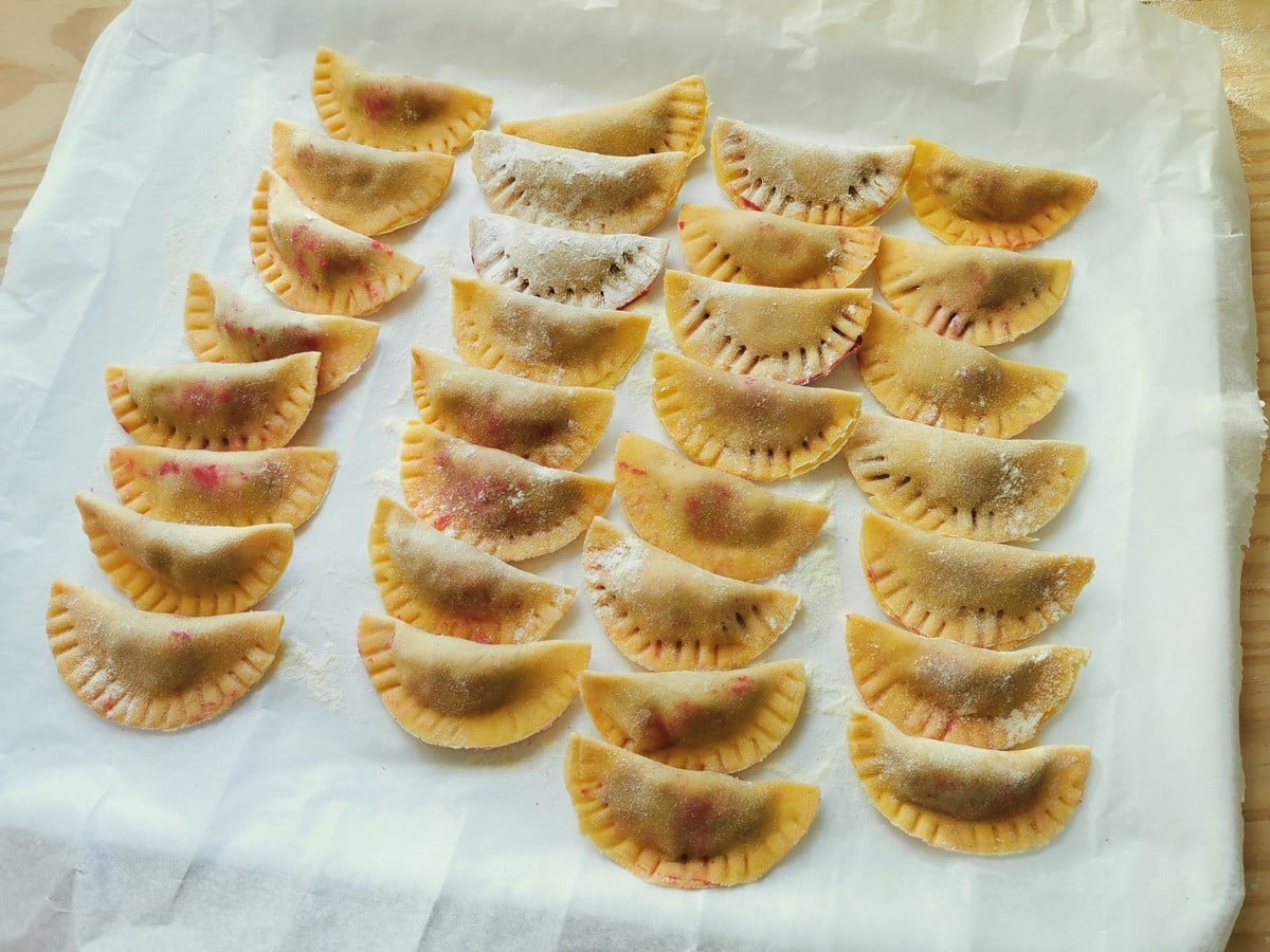 Ready casunziei beetroot ravioli on tray covered with oven paper.