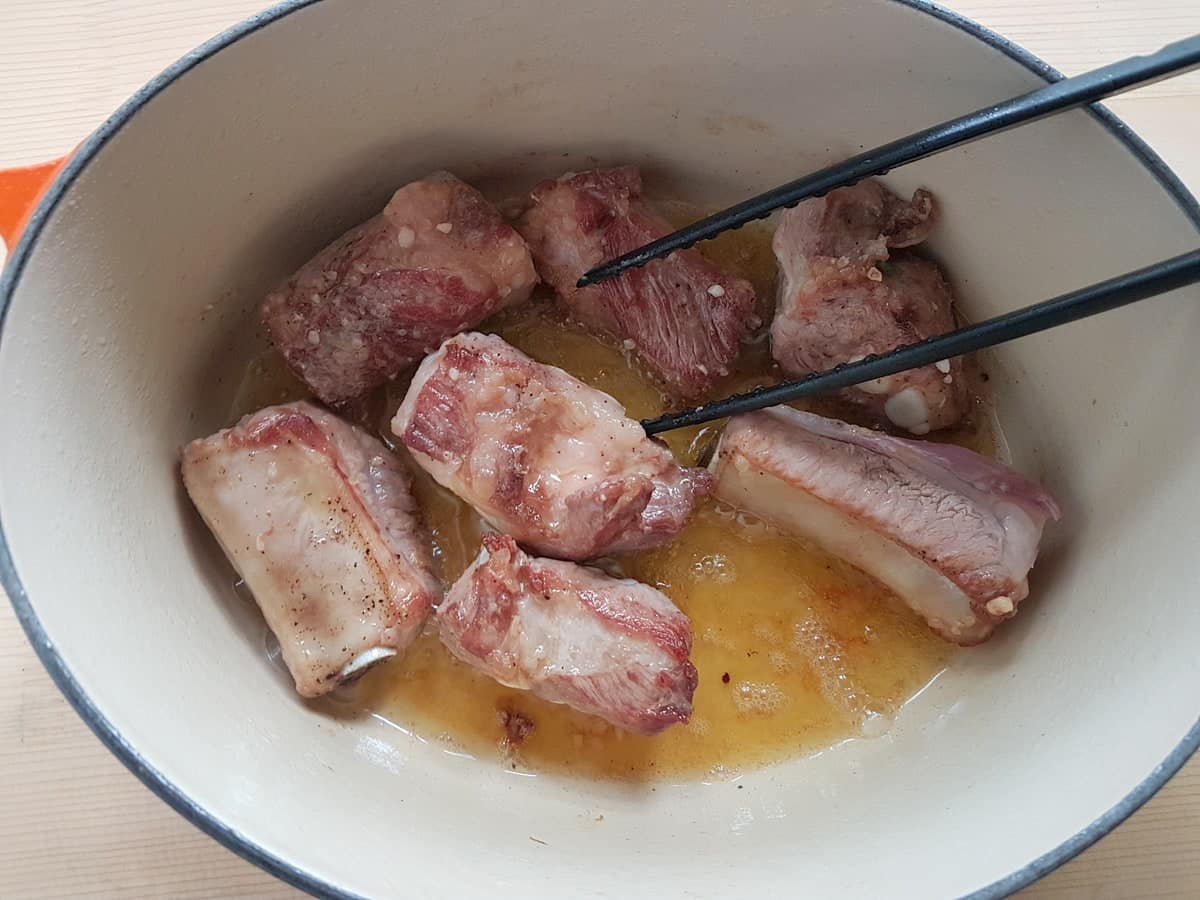 pork ribs browning in olive oil in Dutch oven