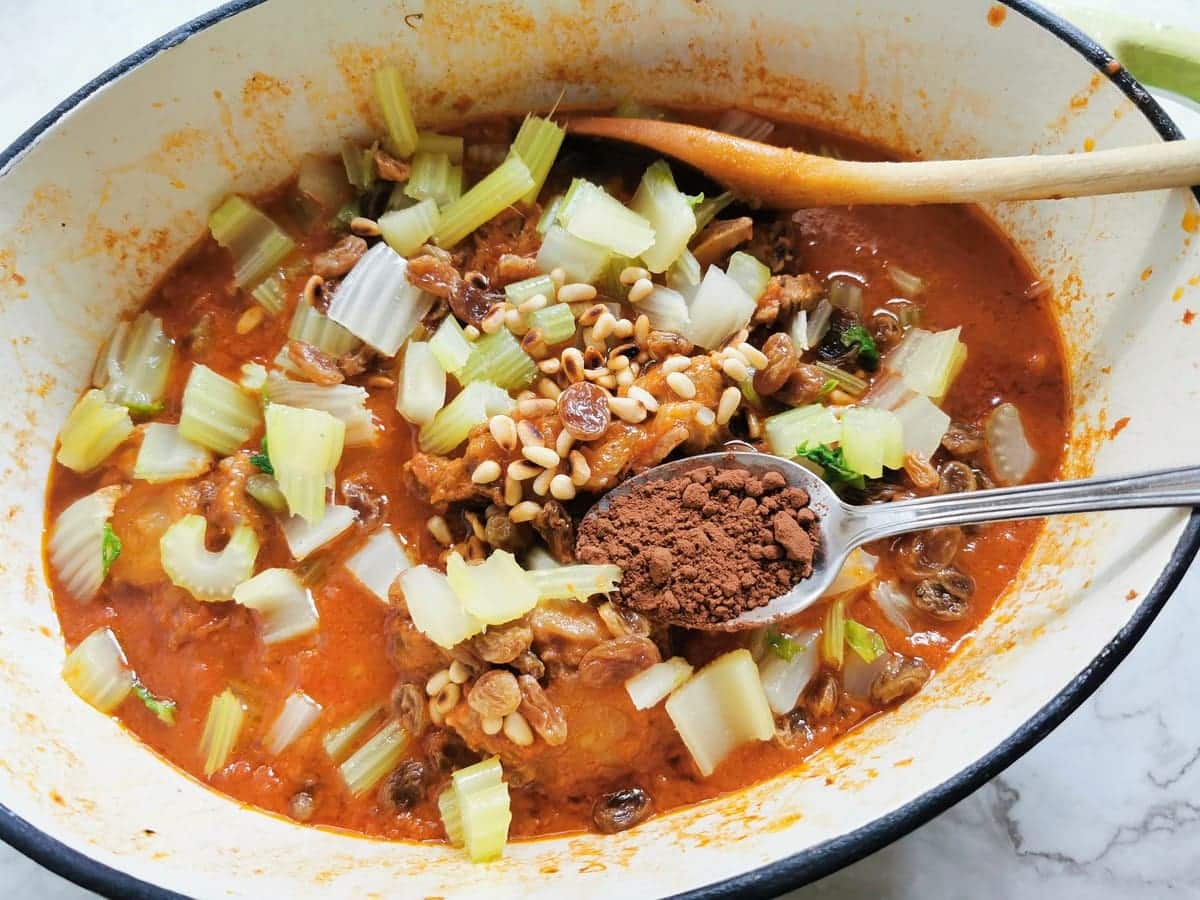 pine nuts, raisins, boiled celery and cocoa powder added to oxtail stew in Dutch oven.