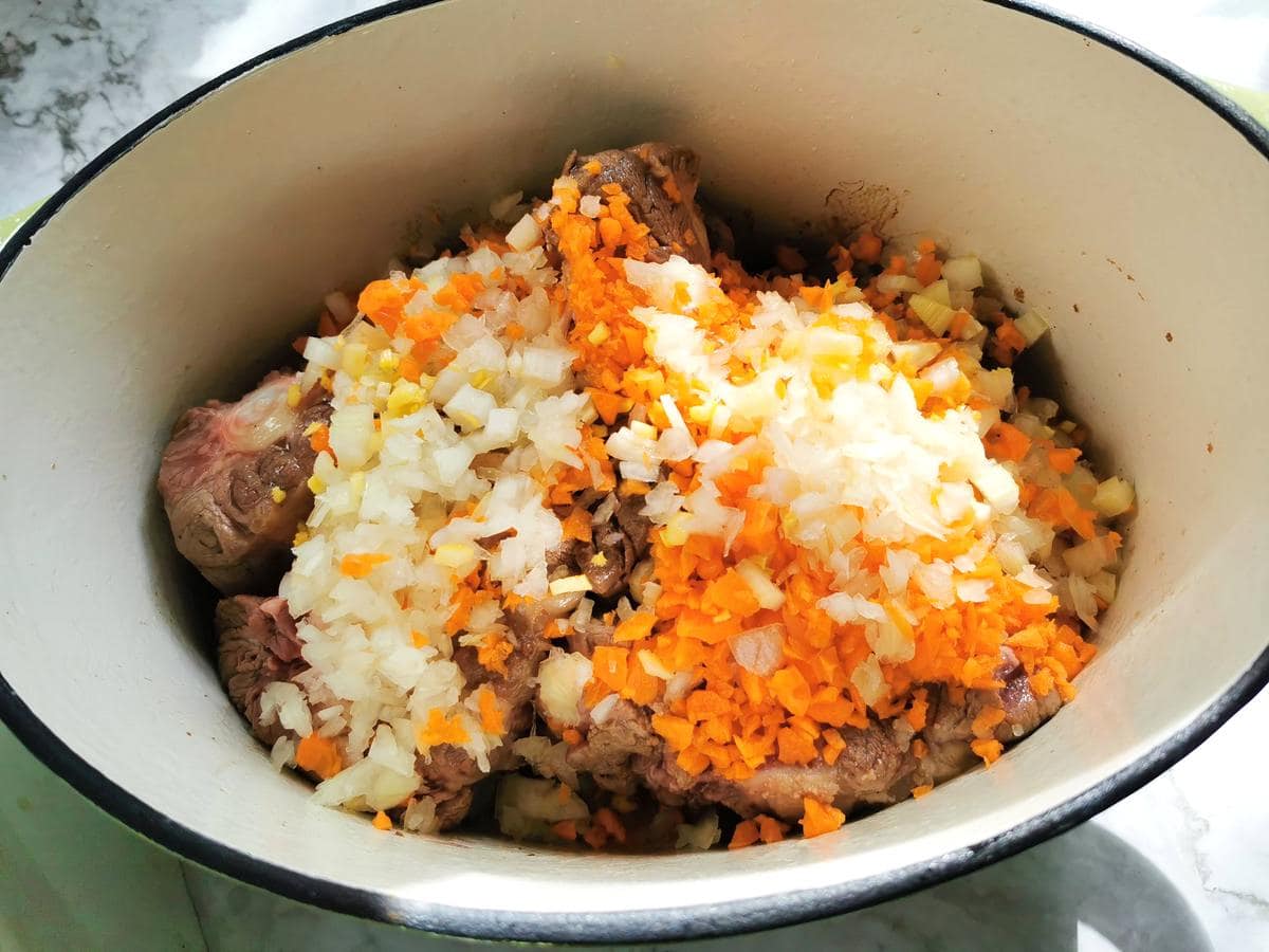 finely chopped onion, carrot and celery in Dutch oven with oxtail pieces.