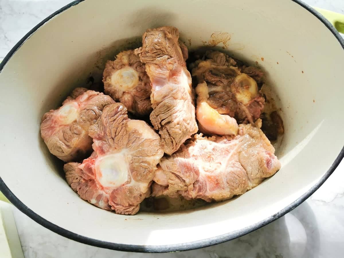 browned oxtail pieces in Dutch oven.