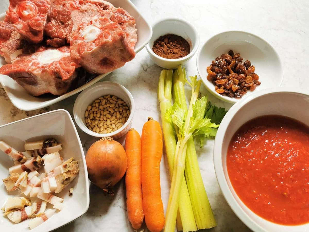 Ingredients for oxtail ragu, celery, carrots, onion, tomato passata, guanciale, raisins, pine nuts, cocoa and oxtail.