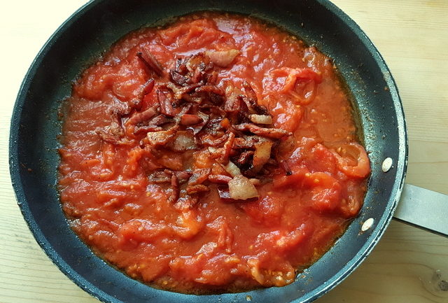 fresh tomato sauce and crispy pork cheek in frying pan