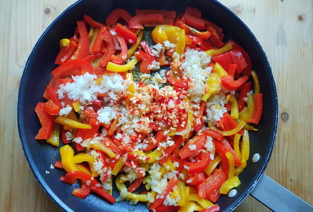 cut bell peppers, chopped onions, red chili pepper and garlic in frying pan