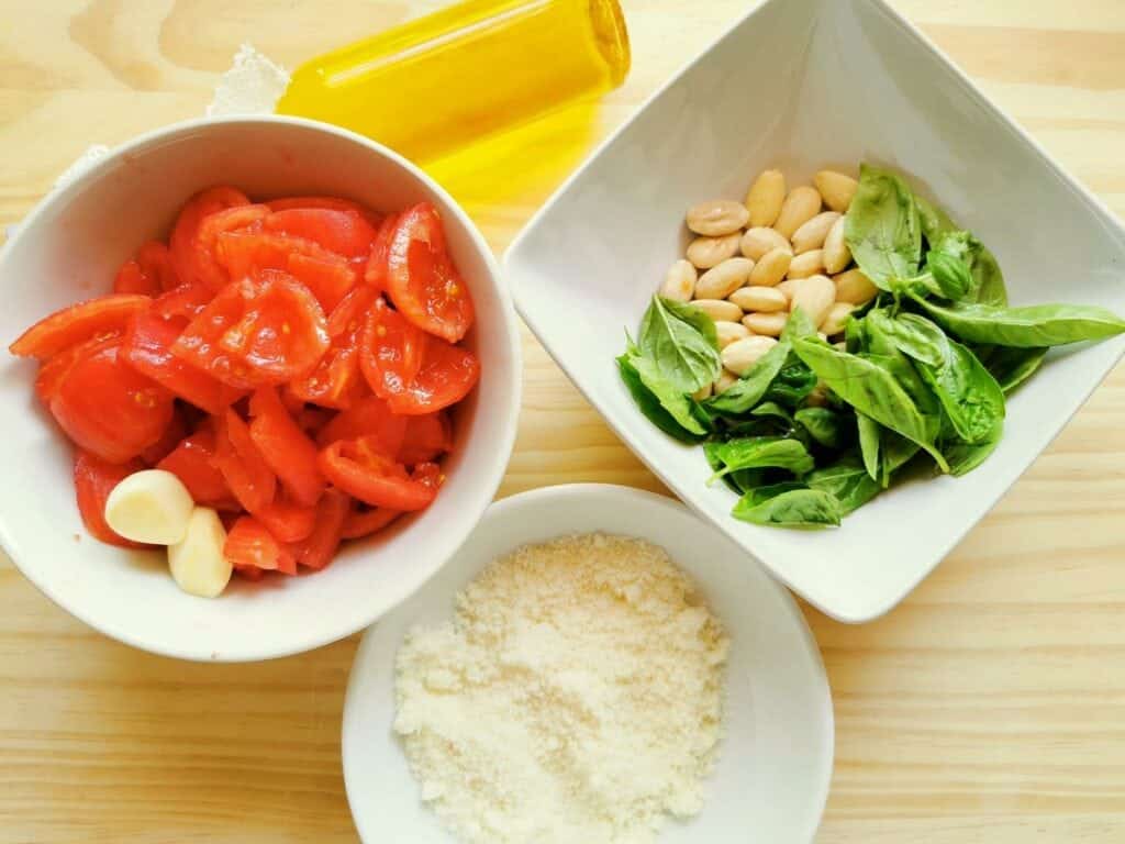 prepared ingredients for Trapanes pesto in white bowls. 