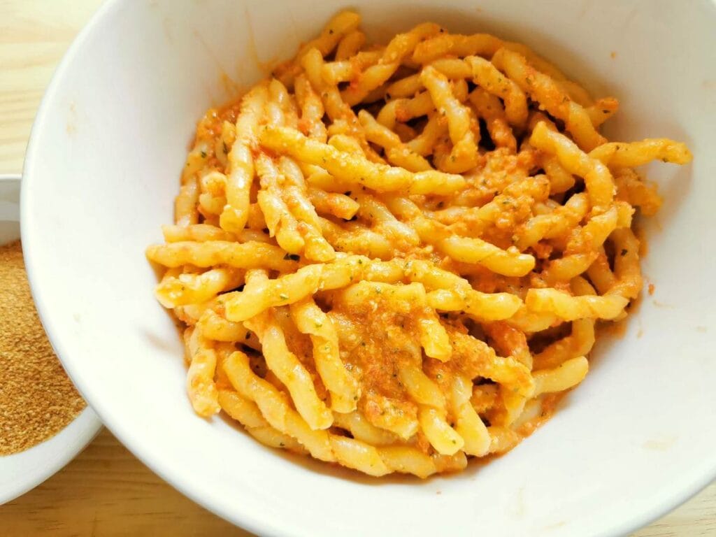 cooked busiate pasta mixed with Trapanese pesto in white bowl