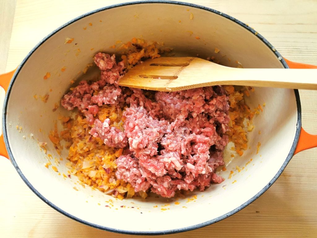 ground meat added to onions, carrots and celery in Dutch oven