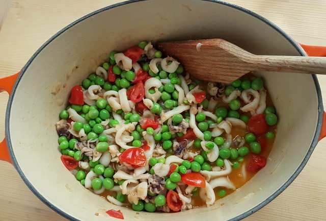 onions, cuttlefish, tomatoes and peas cooking in Dutch oven