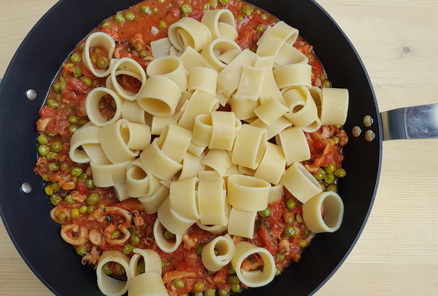 calamarata pasta in skillet with stewed cuttlefish sauce