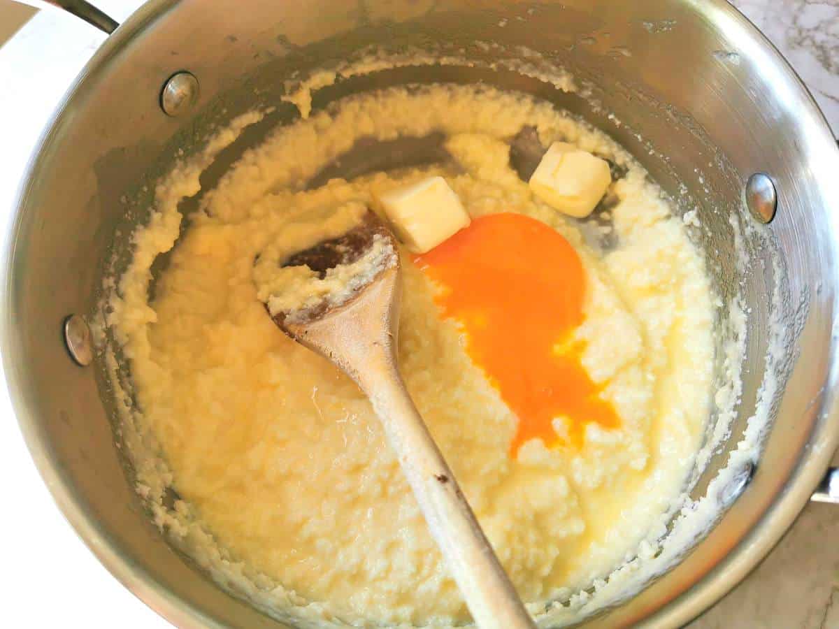 Pieces of butter and an egg yolk added to melted Fontina cheese.