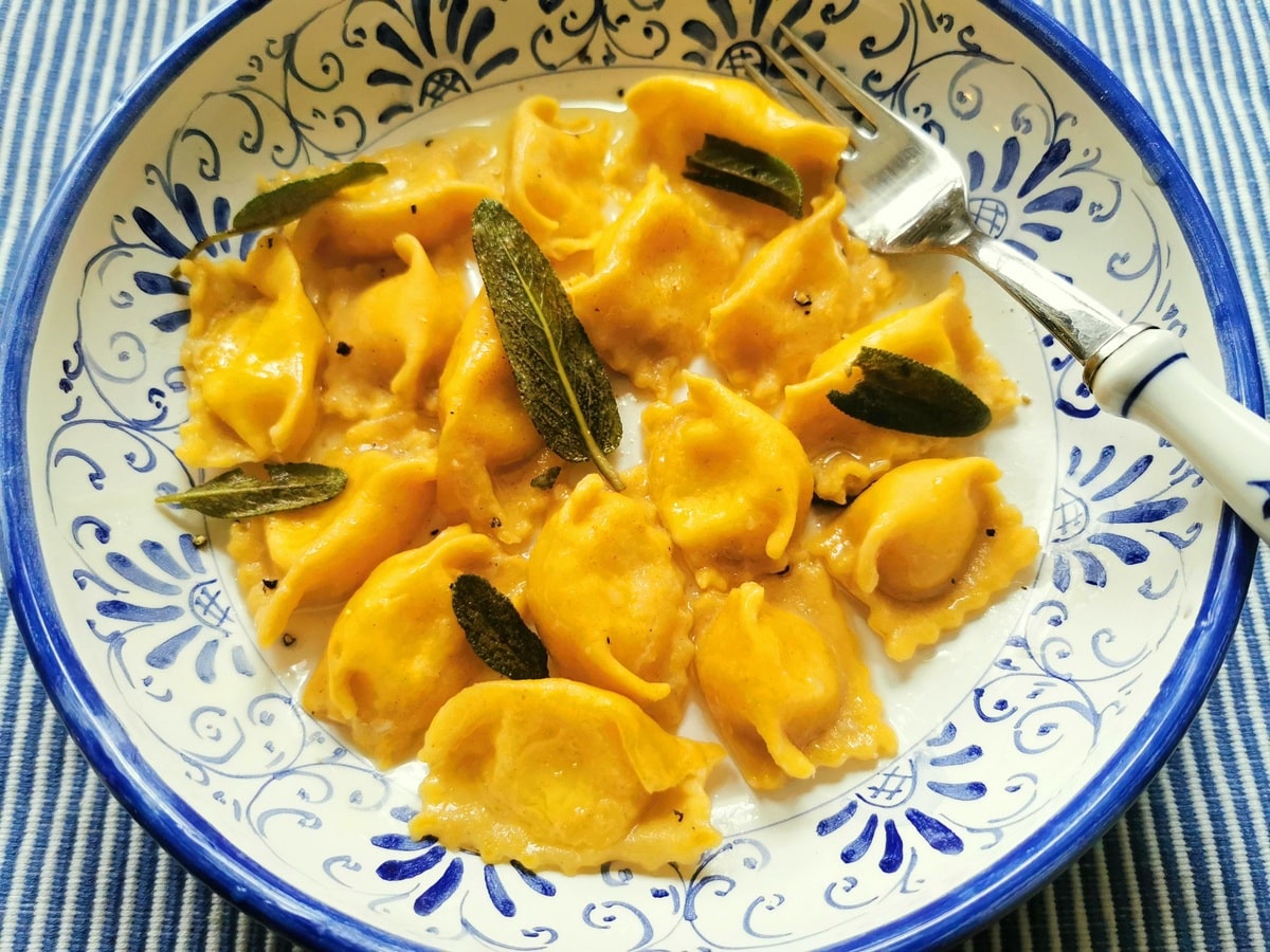 agnolotti pasta that has been filled with cheese, cooked and served with a sage butter sauce on a plate