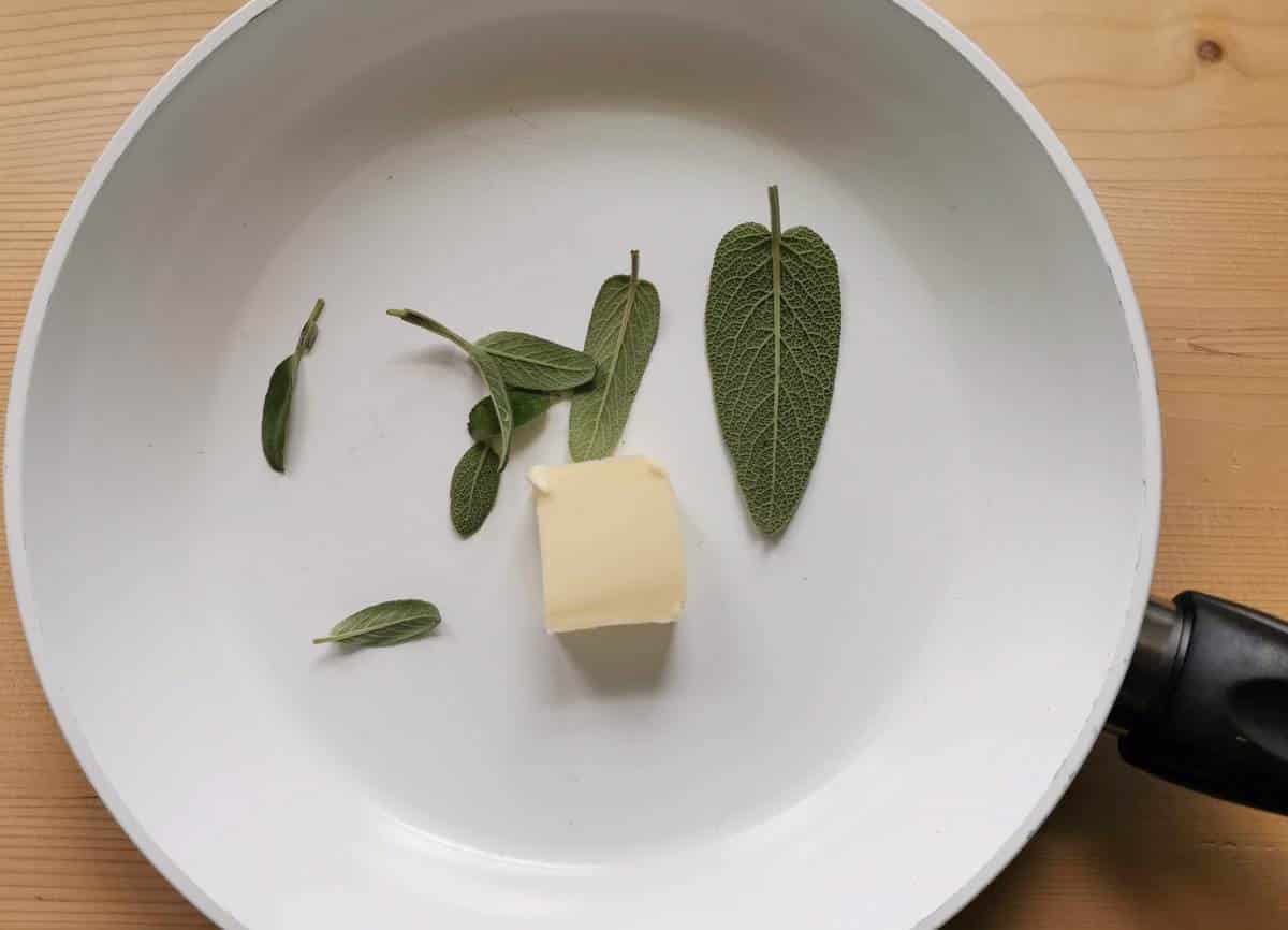 pieces of butter and fresh sage leaves in frying pan