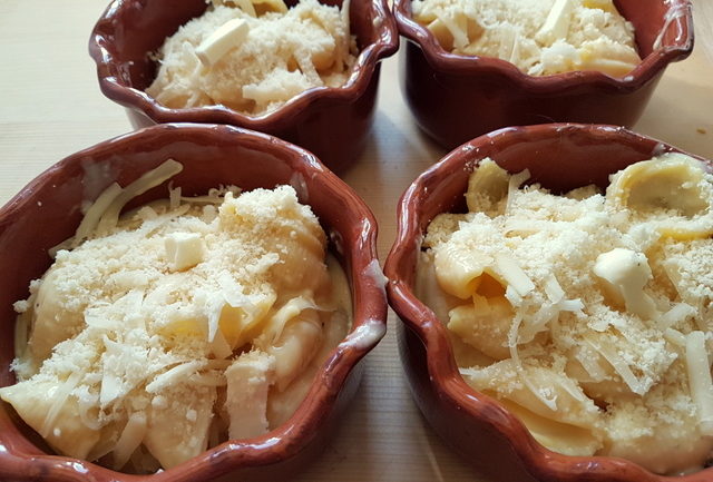 Cheesy conchiglie pasta al forno (baked pasta shells) in individual terracotta dishes before baking