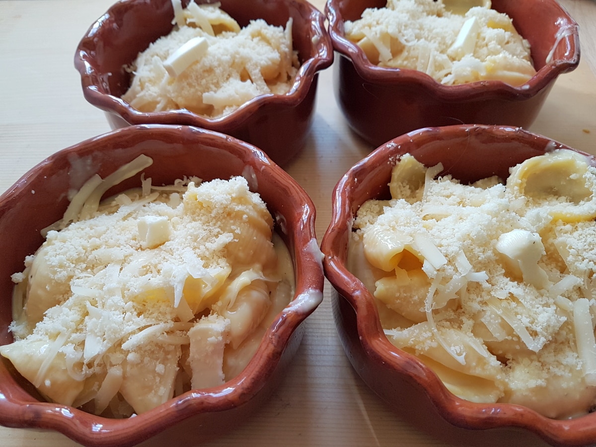 Individual portions of cheesy conchiglie al forn (baked pasta shells) ready to go in the oven.