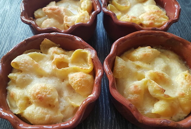 Cheesy conchiglie pasta al forno (baked pasta shells) in individual terracotta oven dishes