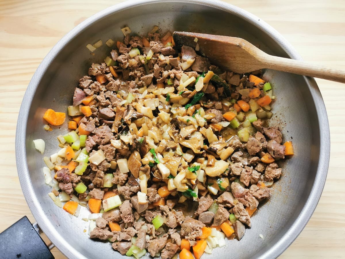 cooked porcini mushrooms in deep frying pan with cooked liver and vegetables