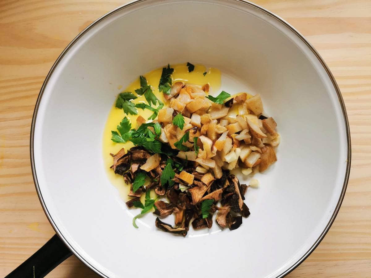 Frozen and dried porcini in deep frying pan with olive oil, garlic and parsley