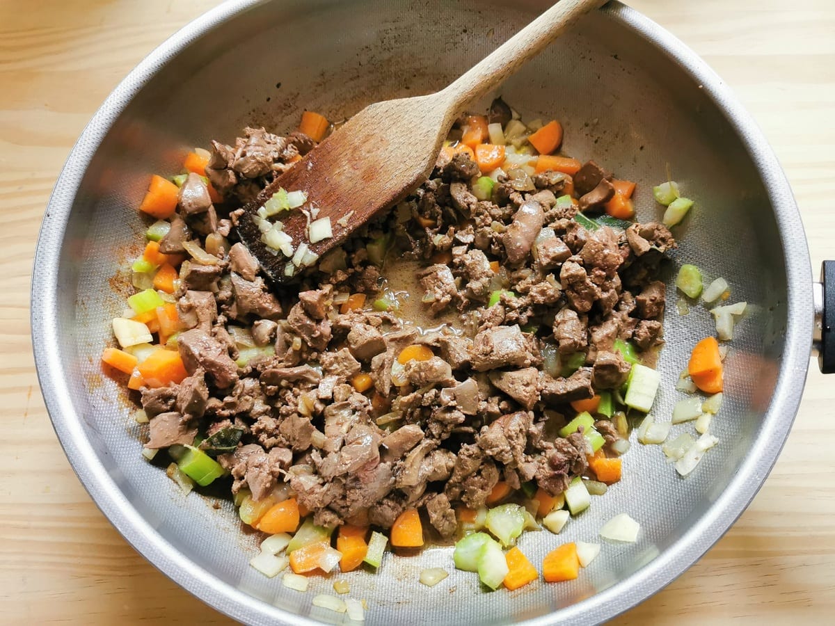 Cooked chicken livers in deep frying pan with chopped onions, celery and carrots