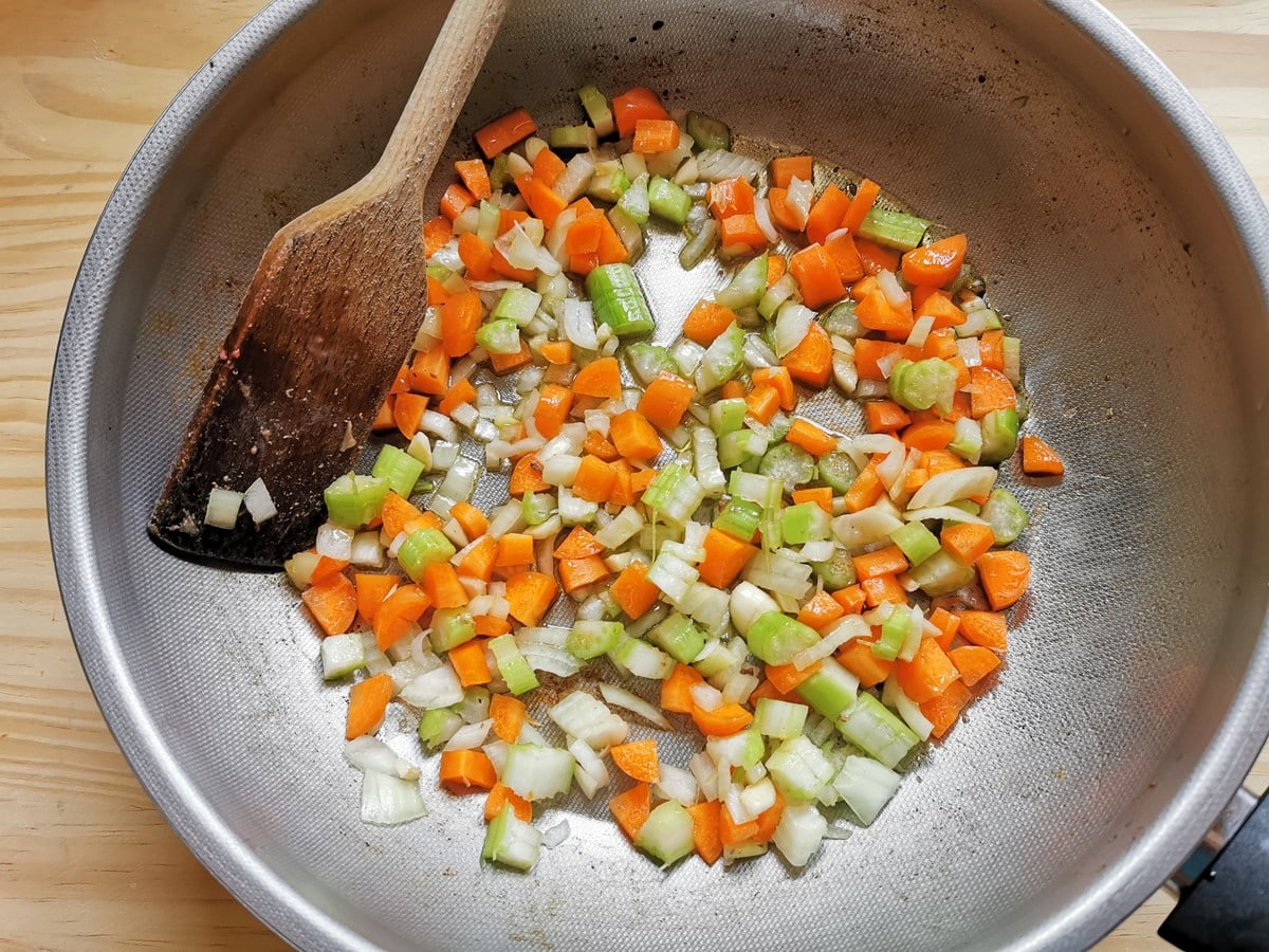 chopped onions, celery and carrots cooking in olive oil in deep frying pan.