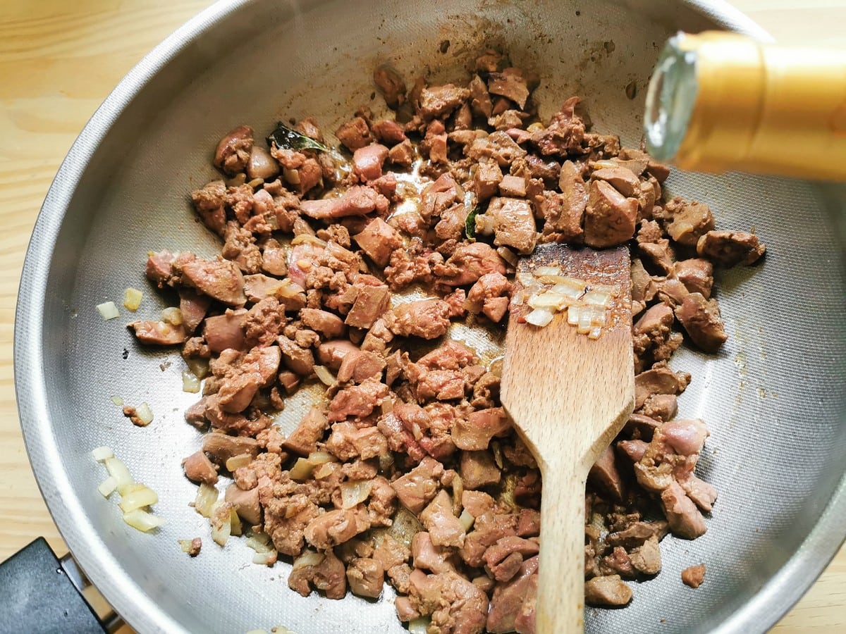 wine added to chicken livers cooking in deep frying pan