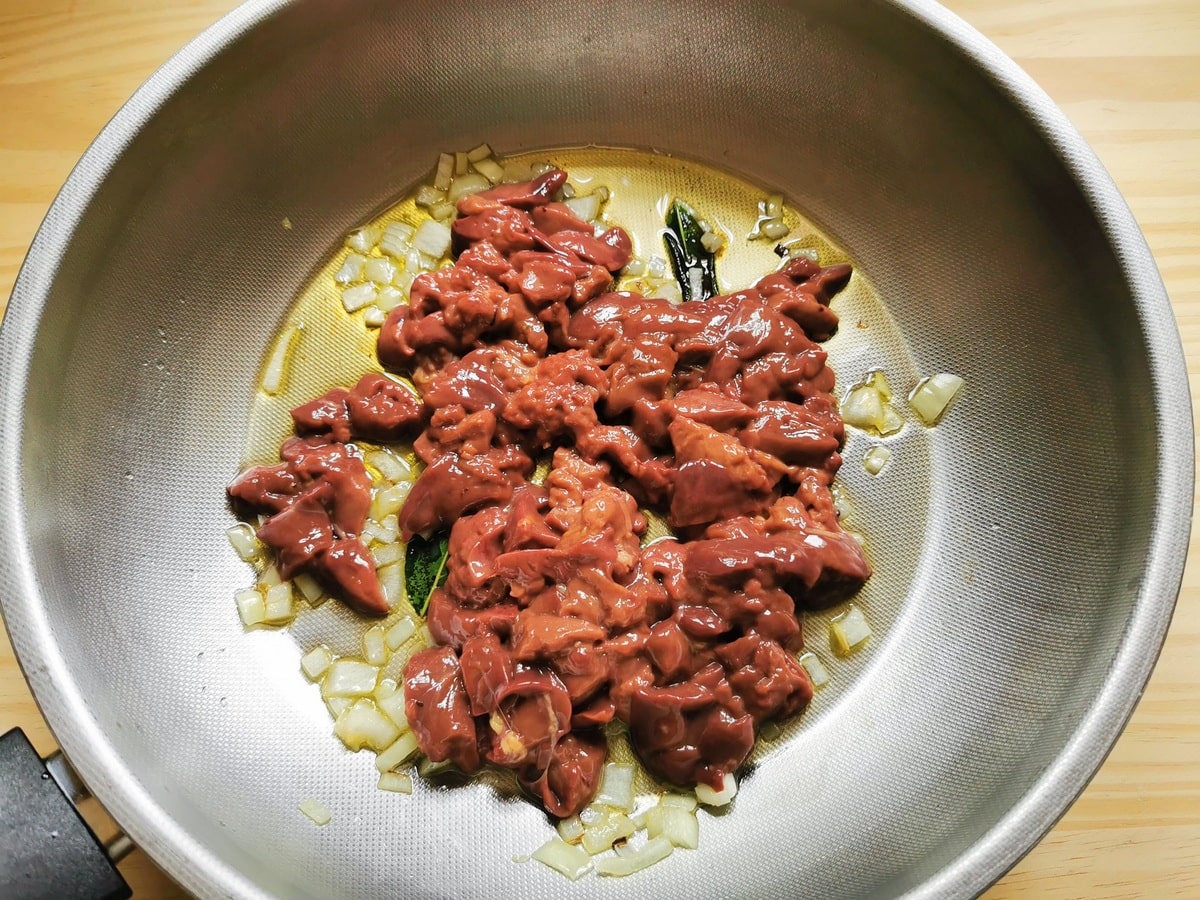 chopped chicken livers in deep frying pan with olive oil, onions and bay leaves