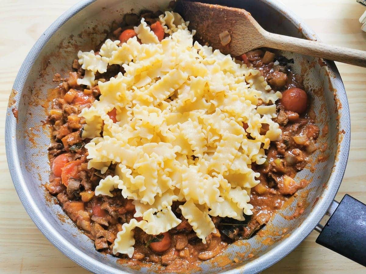 cooked short mafalda pasta in pan with chicken liver and porcini ragu