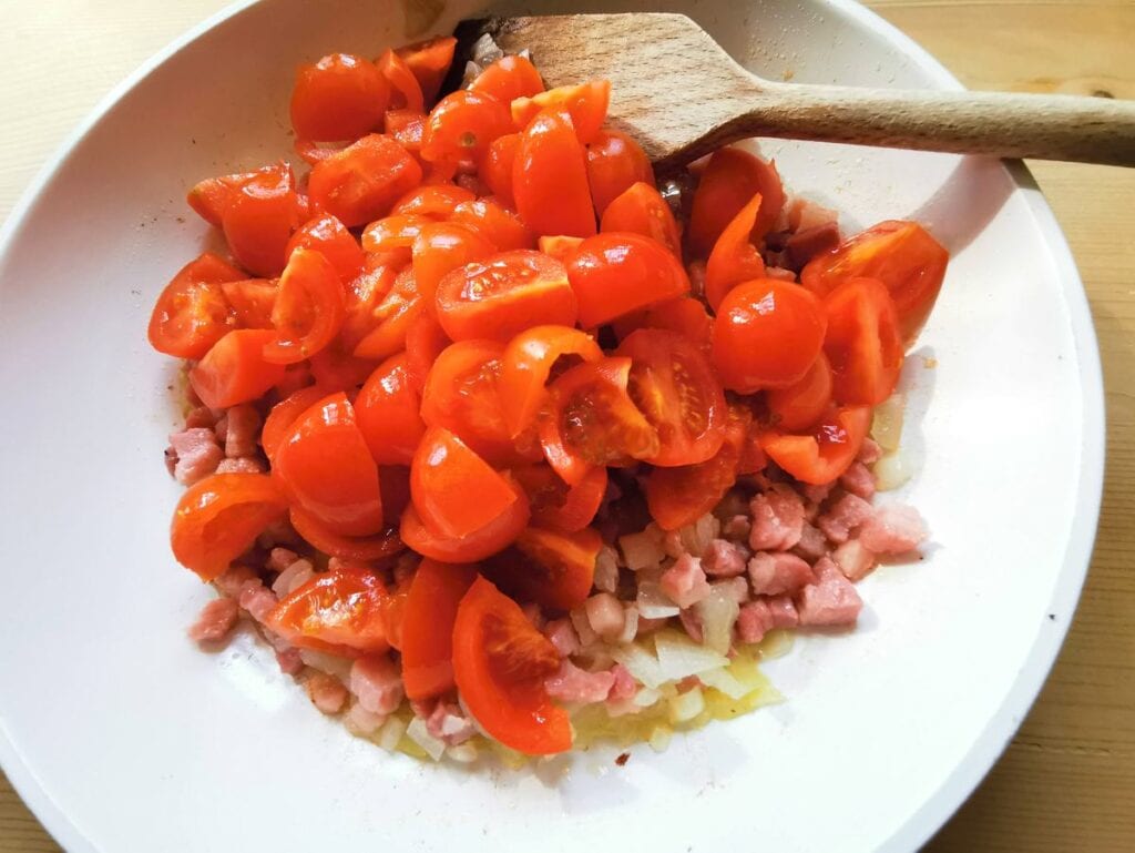 Cherry tomatoes in pan with pancetta and onion