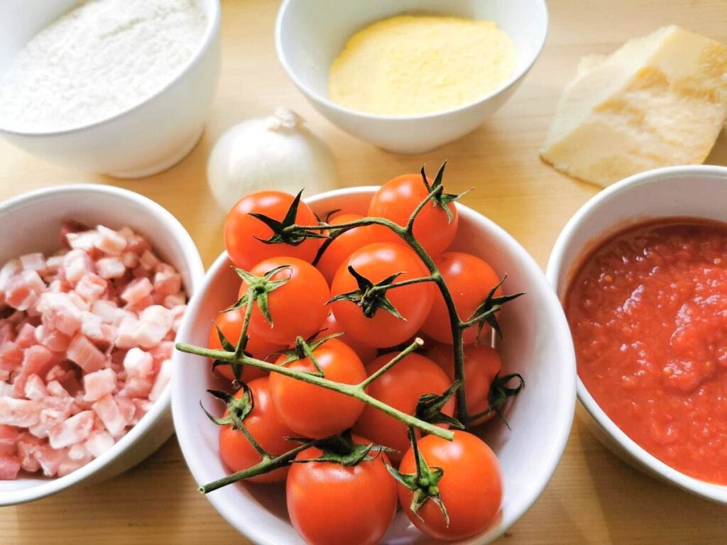 ingredients for corn and wheat flour patellette with pancetta and tomato sauce in different white bowls