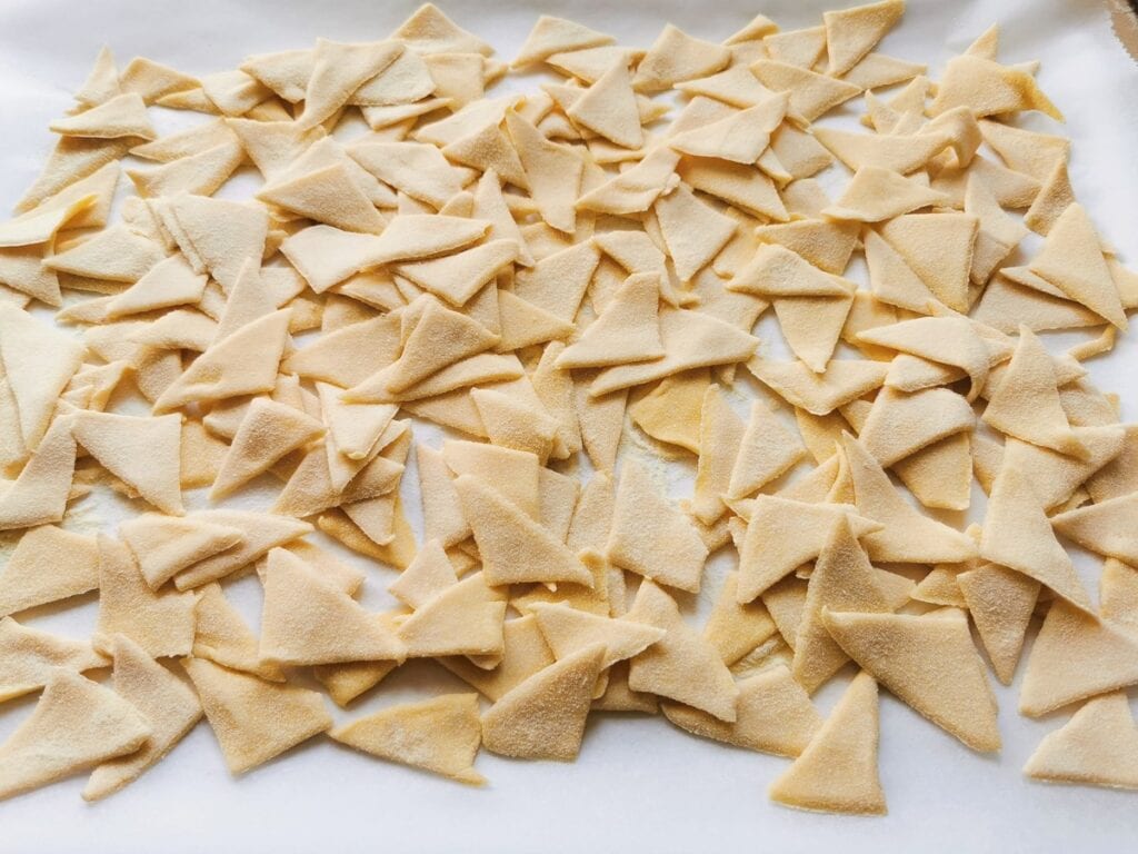 corn and wheat flour pasta triangles on white baking paper.