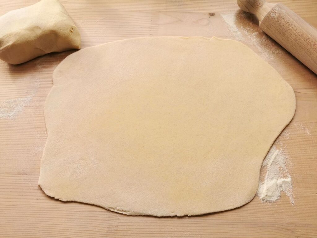 dough rolled out into a sheet on a wooden pastry board