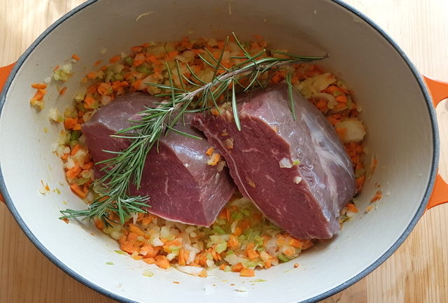 Chopped vegetables and large pieces of beef in Dutch oven