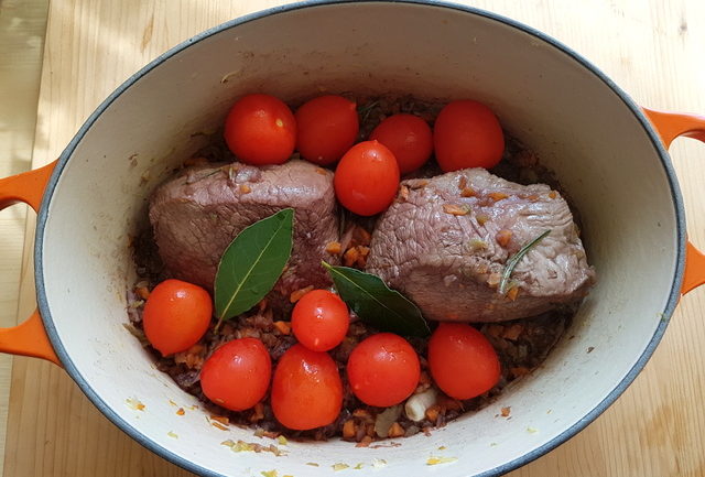 Tomatoes added to beef and vegetables in Dutch oven